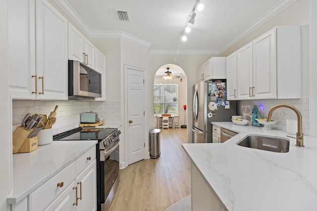 1009 Forest Shore Dr, Miramar Beach, FL 32550 - kitchen featuring appliances with stainless steel finishes, white cabinets, light wood-style floors, a ceiling fan, and ornamental molding