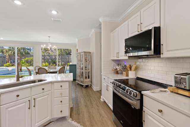1009 Forest Shore Dr, Miramar Beach, FL 32550 - kitchen featuring appliances with stainless steel finishes, a chandelier, tasteful backsplash, light countertops, and white cabinetry