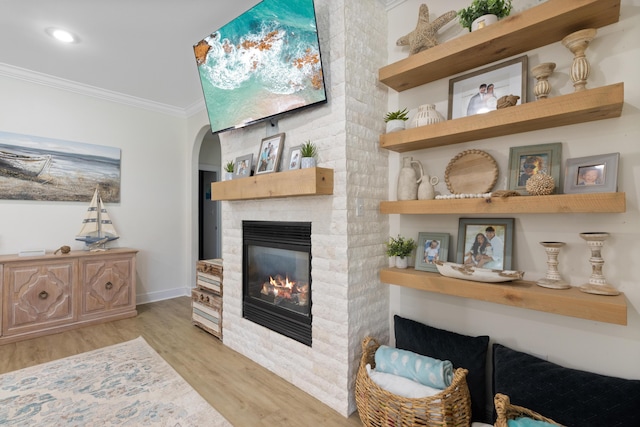 1009 Forest Shore Dr, Miramar Beach, FL 32550 - living room with light wood-style flooring, crown molding, a glass covered fireplace, arched walkways, and recessed lighting
