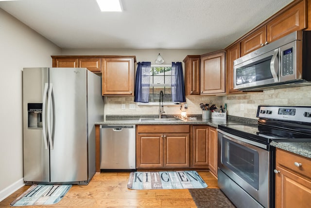 2808 Ping Ln, Crestview, FL 32539 - kitchen featuring appliances with stainless steel finishes, decorative backsplash, brown cabinetry, and light wood-style flooring