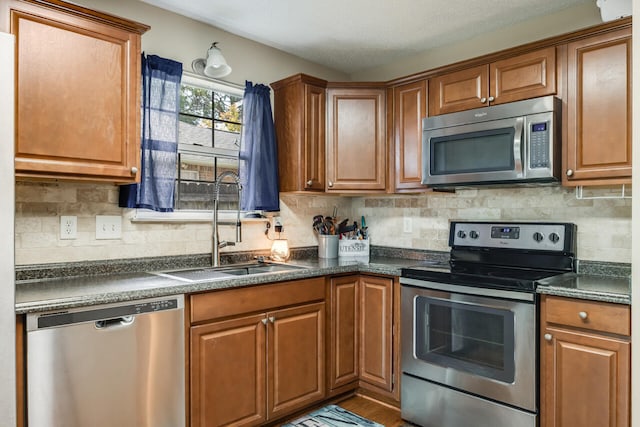 2808 Ping Ln, Crestview, FL 32539 - kitchen featuring stainless steel appliances, dark countertops, brown cabinetry, and decorative backsplash