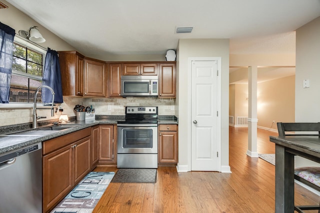 2808 Ping Ln, Crestview, FL 32539 - kitchen with appliances with stainless steel finishes, light wood-type flooring, dark countertops, and tasteful backsplash