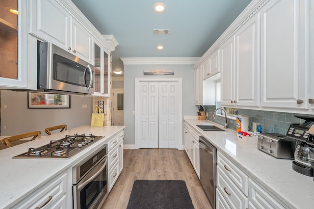 102 Terra Cotta Way, Destin, FL 32541 - kitchen featuring stainless steel appliances, white cabinets, crown molding, glass insert cabinets, and light wood-style flooring