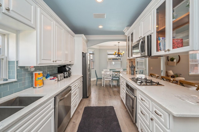 102 Terra Cotta Way, Destin, FL 32541 - kitchen with stainless steel appliances, white cabinetry, arched walkways, crown molding, and a chandelier