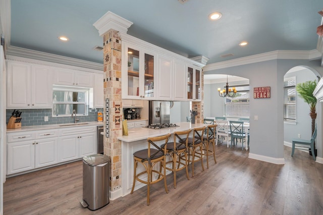 102 Terra Cotta Way, Destin, FL 32541 - kitchen featuring crown molding, arched walkways, decorative backsplash, light countertops, and white cabinets