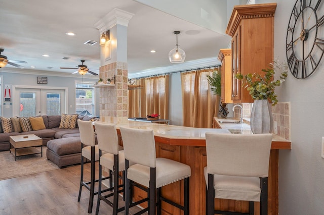 102 Terra Cotta Way, Destin, FL 32541 - kitchen with a ceiling fan, brown cabinets, wood finished floors, crown molding, and a peninsula
