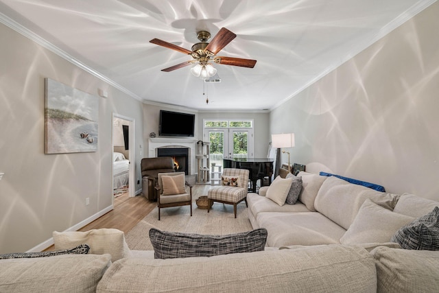 172 Shady Ln, Freeport, FL 32439 - living area featuring ornamental molding, wood finished floors, ceiling fan, a warm lit fireplace, and french doors