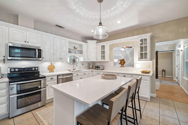 172 Shady Ln, Freeport, FL 32439 - kitchen with stainless steel appliances, light tile patterned floors, glass insert cabinets, a breakfast bar, and recessed lighting