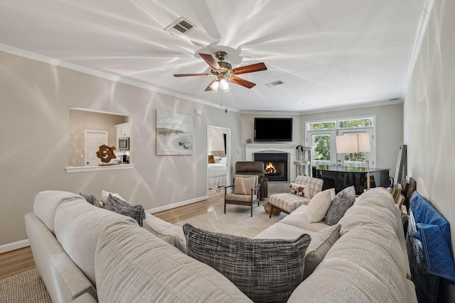 172 Shady Ln, Freeport, FL 32439 - living room featuring wood finished floors, crown molding, a warm lit fireplace, and a ceiling fan