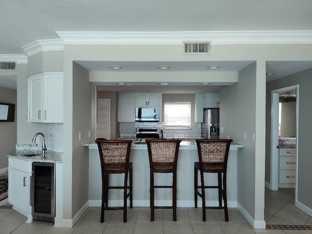 955 Scenic Gulf Dr Unit 410, Miramar Beach, FL 32550 - kitchen with wine cooler, stainless steel appliances, backsplash, a peninsula, and ornamental molding
