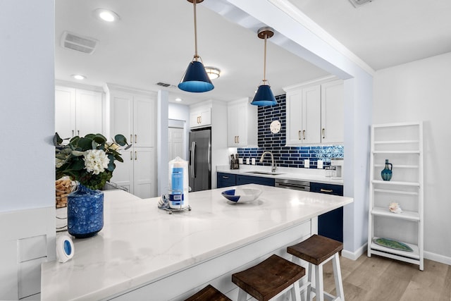 727 Sandpiper Pl # 10516, Miramar Beach, FL 32550 - kitchen featuring appliances with stainless steel finishes, a breakfast bar area, decorative light fixtures, light wood-style floors, and white cabinetry
