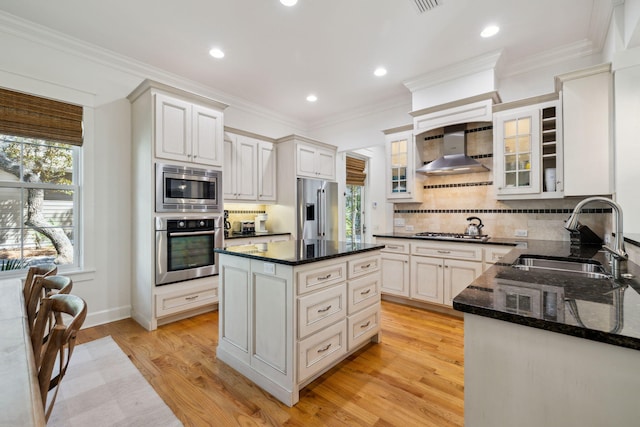 9 W Salt Box Ln, Watersound, FL 32461 - kitchen featuring stainless steel appliances, wall chimney exhaust hood, decorative backsplash, light wood finished floors, and dark stone counters