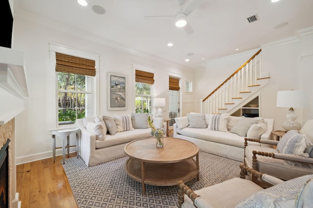 9 W Salt Box Ln, Watersound, FL 32461 - living room featuring stairs, a fireplace, ceiling fan, light wood-style flooring, and crown molding