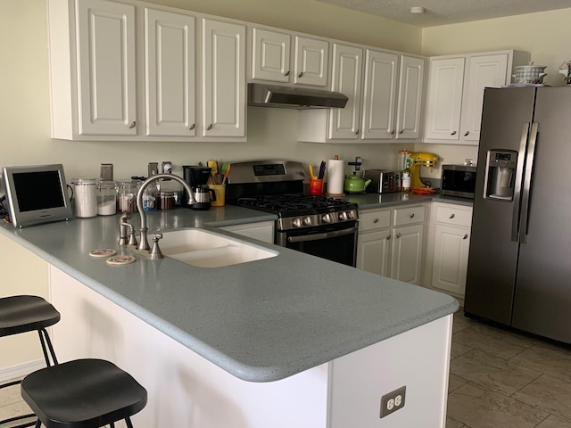 4643 Windstarr Dr, Destin, FL 32541 - kitchen featuring appliances with stainless steel finishes, under cabinet range hood, white cabinets, and a kitchen bar