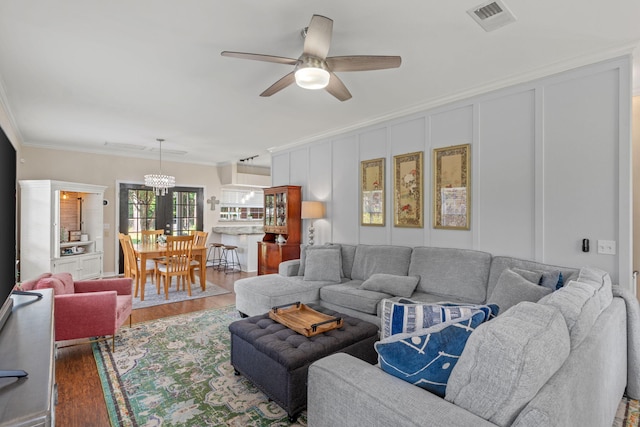3228 Mcmillan Creek Dr, Milton, FL 32583 - living area featuring ornamental molding, wood finished floors, a ceiling fan, a decorative wall, and a chandelier