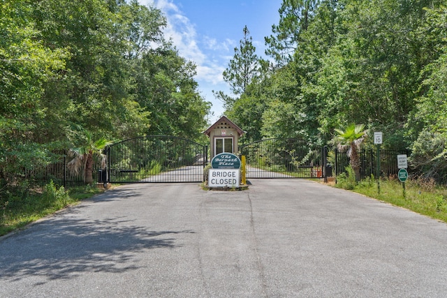 3228 Mcmillan Creek Dr, Milton, FL 32583 - view of asphalt road with a gate, traffic signs, and a gated entry