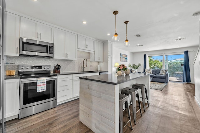 115 Gulf Winds Ct Unit 2, Destin, FL 32541 - kitchen featuring appliances with stainless steel finishes, dark countertops, open floor plan, backsplash, and wood finished floors