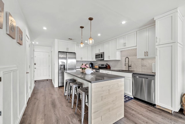 115 Gulf Winds Ct Unit 2, Destin, FL 32541 - kitchen featuring appliances with stainless steel finishes, dark countertops, a breakfast bar area, white cabinetry, and wood finished floors