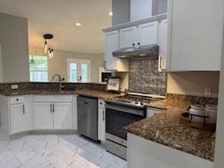 4906 Laurel Oak Dr, Pace, FL 32571 - kitchen with appliances with stainless steel finishes, under cabinet range hood, a peninsula, light marble finish flooring, and dark stone countertops