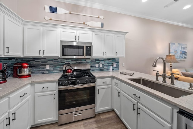 72 Vantage Pt, Miramar Beach, FL 32550 - kitchen with stainless steel appliances, ornamental molding, white cabinets, backsplash, and wood finished floors