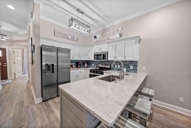 72 Vantage Pt, Miramar Beach, FL 32550 - kitchen featuring appliances with stainless steel finishes, a peninsula, white cabinetry, tasteful backsplash, and light stone counters