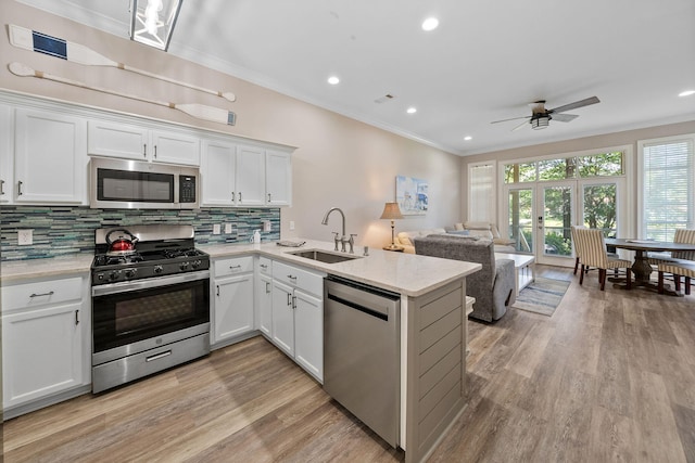 72 Vantage Pt, Miramar Beach, FL 32550 - kitchen featuring appliances with stainless steel finishes, a ceiling fan, backsplash, a peninsula, and light wood-type flooring