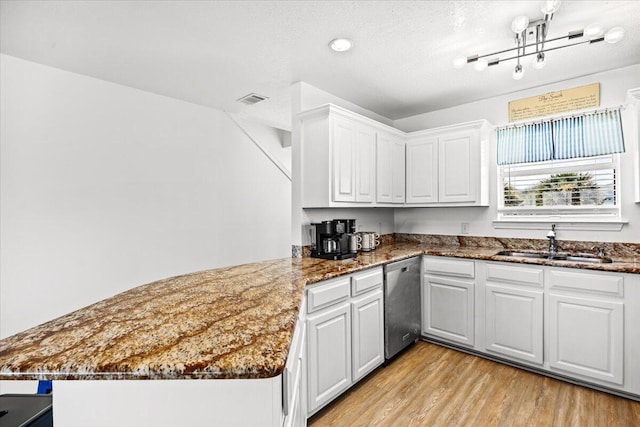 926 Whelk Ct Unit C, Fort Walton Beach, FL 32548 - kitchen featuring stainless steel dishwasher, light wood finished floors, a peninsula, white cabinets, and dark stone counters