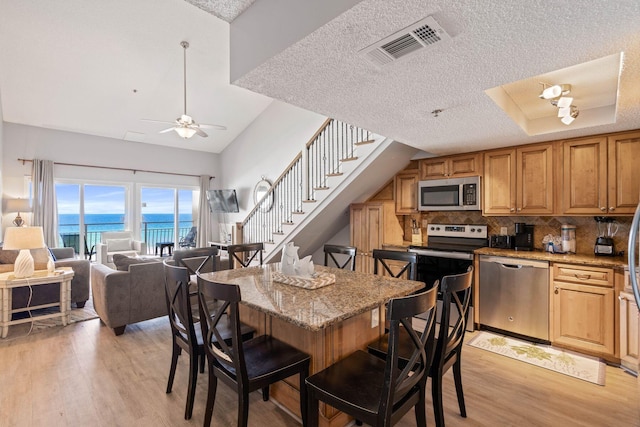 3290 Scenic Highway 98 Unit 305B, Destin, FL 32541 - kitchen featuring appliances with stainless steel finishes, a breakfast bar area, light wood-type flooring, light stone counters, and decorative backsplash