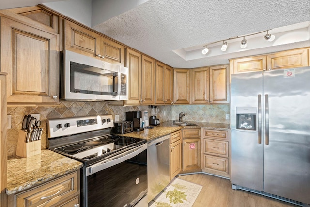 3290 Scenic Highway 98 Unit 305B, Destin, FL 32541 - kitchen with appliances with stainless steel finishes, light wood-style flooring, a textured ceiling, light stone countertops, and tasteful backsplash