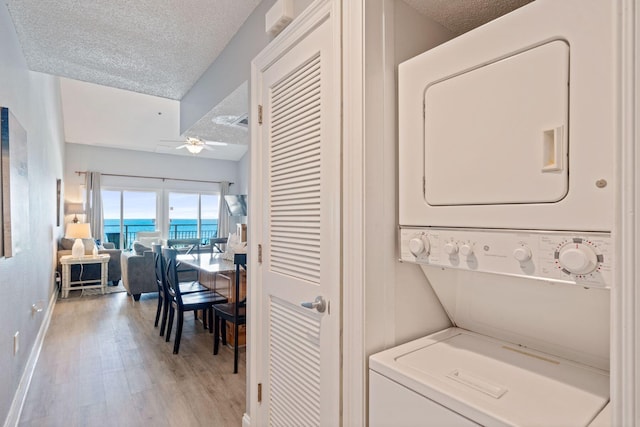 3290 Scenic Highway 98 Unit 305B, Destin, FL 32541 - laundry room with stacked washing machine and dryer, a textured ceiling, light wood-type flooring, a ceiling fan, and a water view