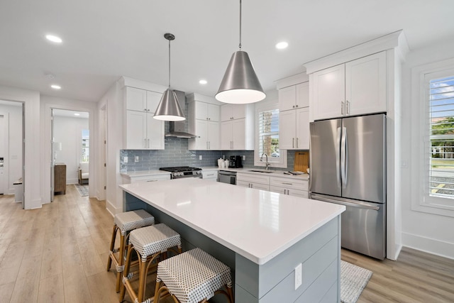 246 Dockside Dr, Port St Joe, FL 32456 - kitchen with appliances with stainless steel finishes, wall chimney range hood, light countertops, light wood finished floors, and backsplash