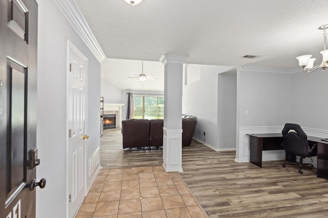 4601 Top Flight Dr, Crestview, FL 32539 - entryway with ornamental molding, ornate columns, a textured ceiling, light wood-type flooring, and a warm lit fireplace