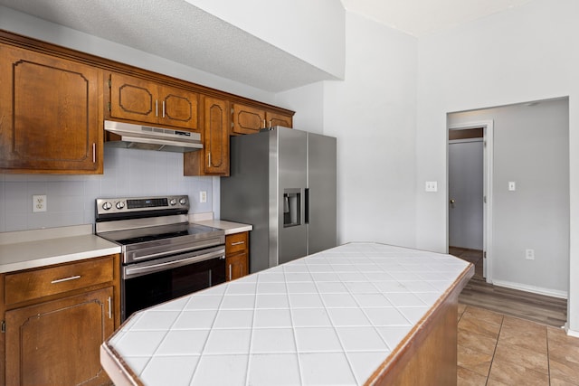4601 Top Flight Dr, Crestview, FL 32539 - kitchen with appliances with stainless steel finishes, under cabinet range hood, a center island, decorative backsplash, and brown cabinetry