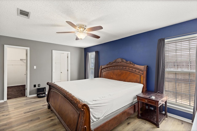 4601 Top Flight Dr, Crestview, FL 32539 - bedroom featuring light wood-style floors, a textured ceiling, ceiling fan, and ensuite bath