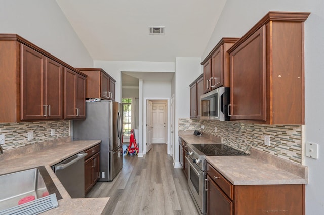 138 Crab Apple Ave, Crestview, FL 32536 - kitchen with appliances with stainless steel finishes, vaulted ceiling, light wood-type flooring, tasteful backsplash, and light countertops