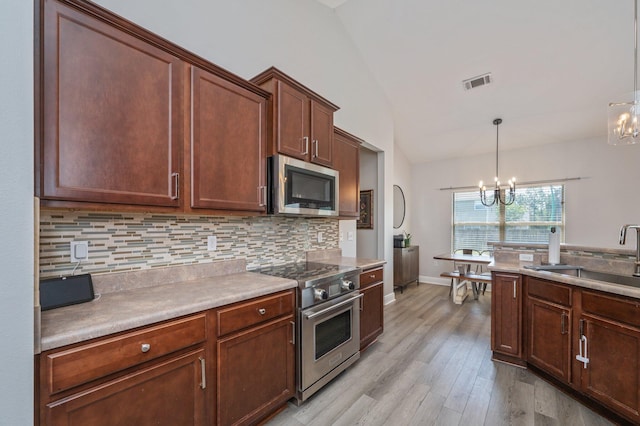 138 Crab Apple Ave, Crestview, FL 32536 - kitchen featuring appliances with stainless steel finishes, a chandelier, lofted ceiling, tasteful backsplash, and light wood-type flooring