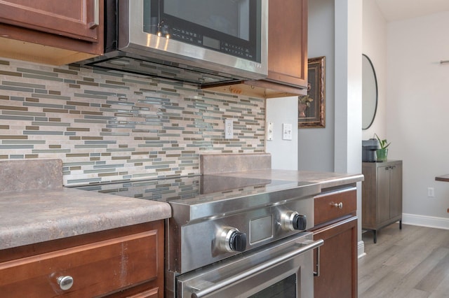 138 Crab Apple Ave, Crestview, FL 32536 - kitchen with appliances with stainless steel finishes, decorative backsplash, light wood-type flooring, and brown cabinets