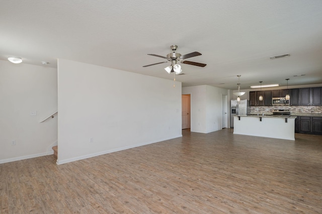 728 Widgeon Way, Crestview, FL 32539 - unfurnished living room with light wood finished floors, a ceiling fan, and stairway