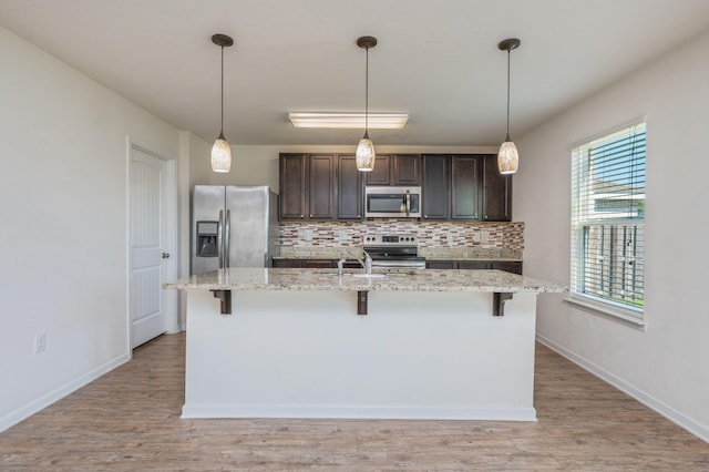 728 Widgeon Way, Crestview, FL 32539 - kitchen featuring appliances with stainless steel finishes, tasteful backsplash, a breakfast bar, dark brown cabinetry, and a kitchen island with sink