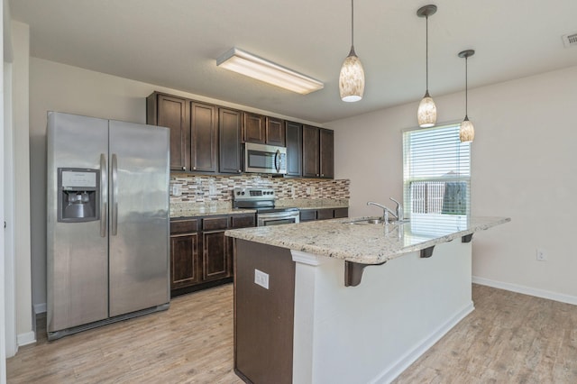 728 Widgeon Way, Crestview, FL 32539 - kitchen with appliances with stainless steel finishes, dark brown cabinets, light wood-style flooring, and backsplash