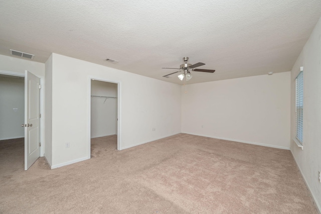 728 Widgeon Way, Crestview, FL 32539 - unfurnished bedroom with light colored carpet, a textured ceiling, a walk in closet, and ceiling fan