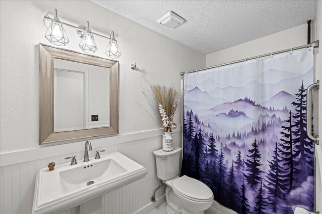 5408 Josh Dr, Crestview, FL 32536 - bathroom featuring a textured ceiling, wainscoting, and a shower with shower curtain