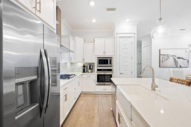 209 Milestone Dr Unit A, Inlet Beach, FL 32461 - kitchen with appliances with stainless steel finishes, ornamental molding, light wood-style floors, white cabinetry, and tasteful backsplash