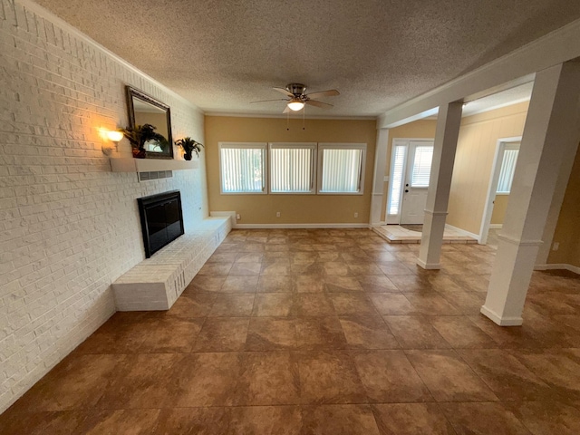 905 Cloverdale Ct, Fort Walton Beach, FL 32547 - unfurnished living room with ceiling fan, brick wall, a brick fireplace, a textured ceiling, and ornate columns