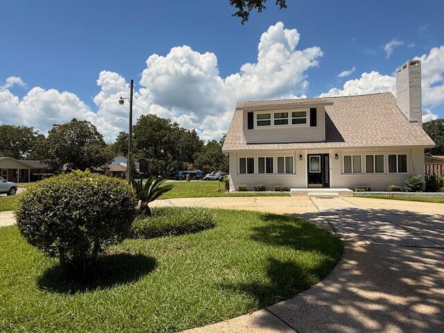 905 Cloverdale Ct, Fort Walton Beach, FL 32547 - view of front of house featuring a front lawn, a chimney, and roof with shingles