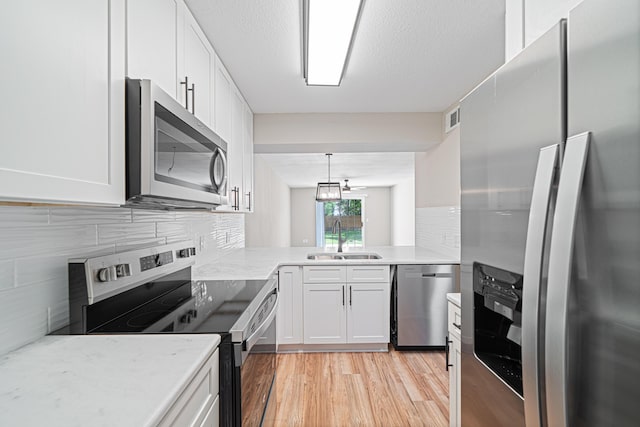 48 4th Ave, Shalimar, FL 32579 - kitchen with stainless steel appliances, backsplash, white cabinetry, and light wood-style flooring