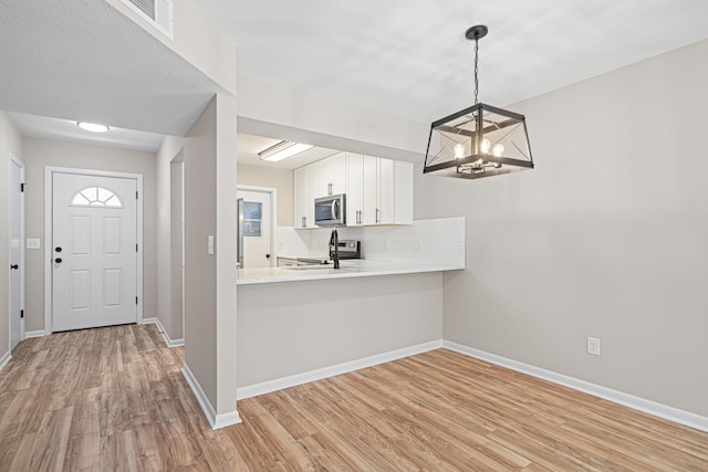 48 4th Ave, Shalimar, FL 32579 - kitchen featuring stainless steel microwave, a chandelier, light wood finished floors, light countertops, and white cabinets