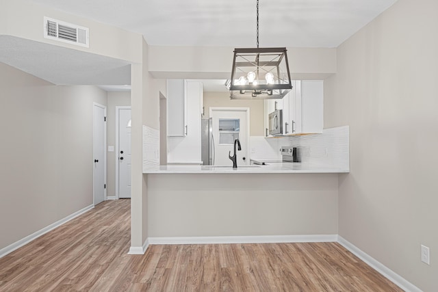 48 4th Ave, Shalimar, FL 32579 - kitchen with stainless steel appliances, a chandelier, light wood-style floors, white cabinetry, and light countertops