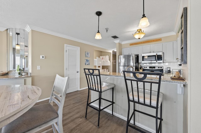 1700 Scenic Highway 98 Unit 101, Destin, FL 32541 - kitchen with stainless steel appliances, a peninsula, crown molding, a breakfast bar area, and dark wood-style floors