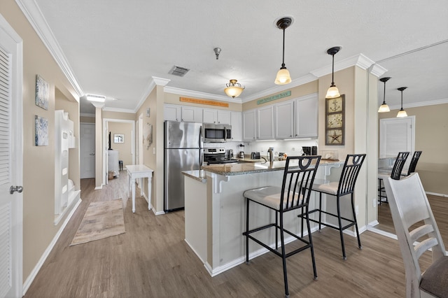 1700 Scenic Highway 98 Unit 101, Destin, FL 32541 - kitchen with appliances with stainless steel finishes, a peninsula, light wood-style floors, a kitchen breakfast bar, and ornamental molding